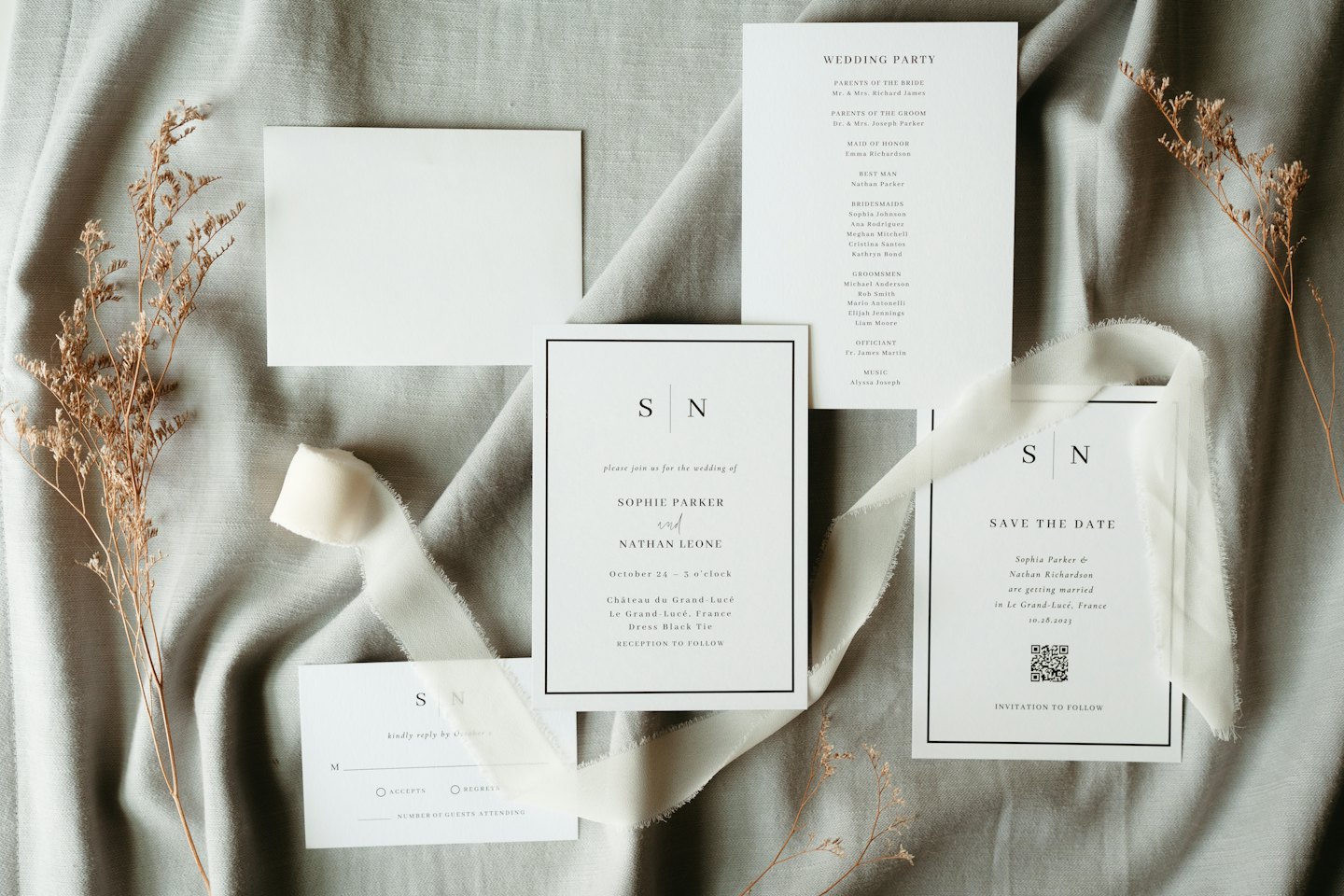 Minimalist white wedding stationery arranged on grey linen.