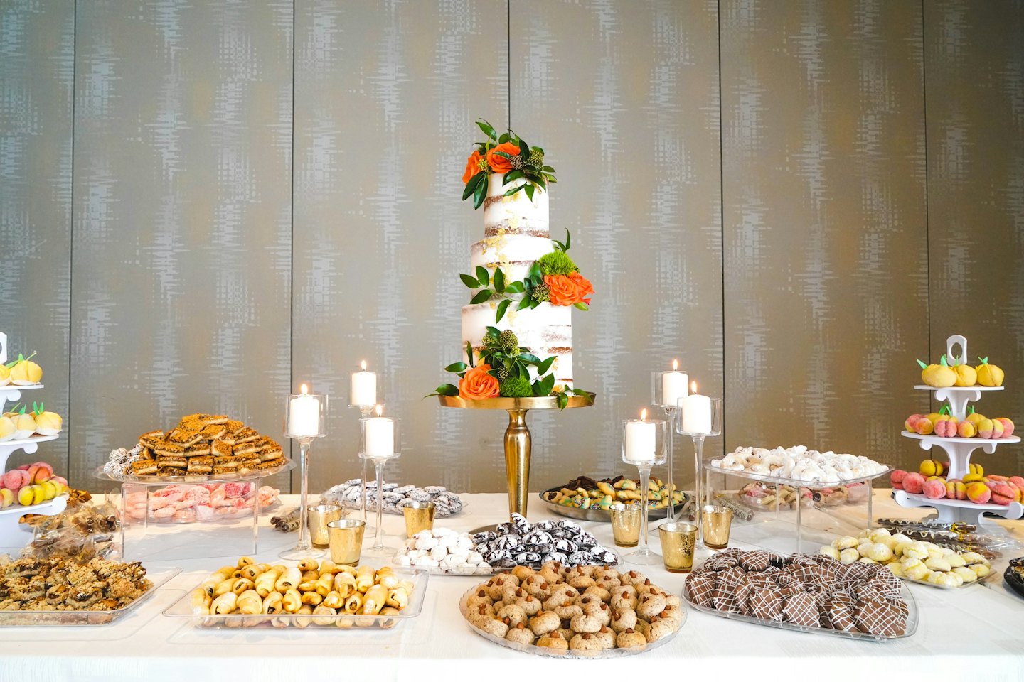 Decorated dessert table with naked wedding cake and pastries.